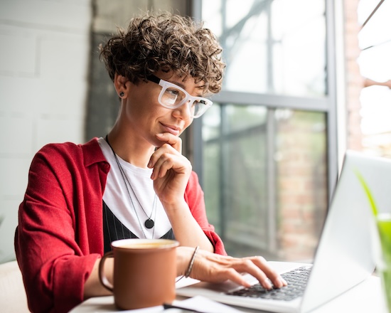 busy young elegant woman in eyeglasses looking at laptop display